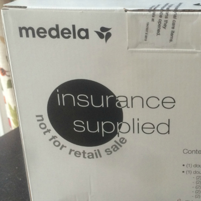 white box with the writing Medela insurance supplied not for retail sale on a black desk with a floral background