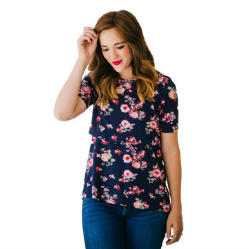 Woman wearing a floral nursing shirt and jeans and looking down at the ground