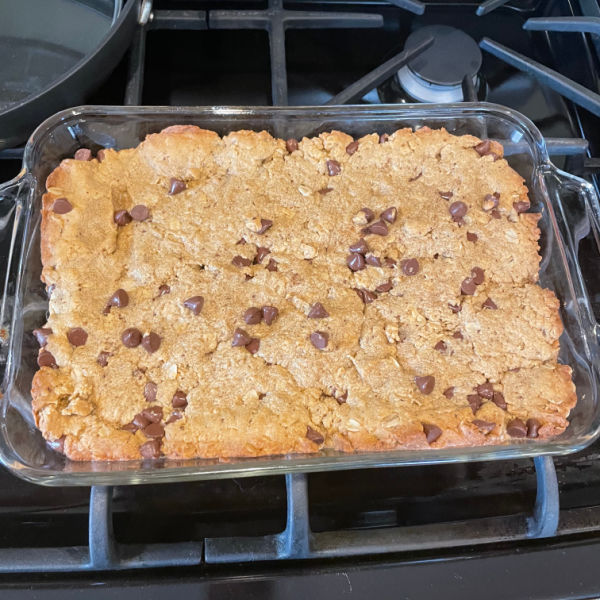 Peanut butter chocolate chip lactation cookie bars in the pan sitting on a stove