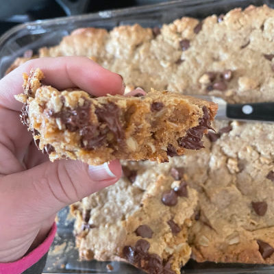Peanut Butter Chocolate Chip Lactation Bars | lactation cookie bar held up in front of cookie pan