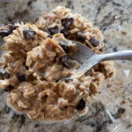 peanut butter lactation overnight oats on a spoon with the bowl full of overnight oats in the background