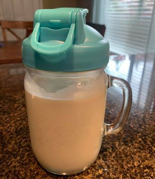 mason jar full of breast milk with a green spout sitting on a granite countertop
