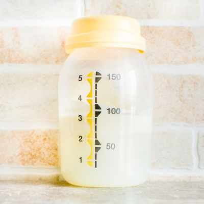 Medela bottle with 2-3 oz of breast milk in it sitting on a counte