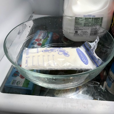lansinoh breast milk bag sitting in a clean bowl thawing in the refrigerator