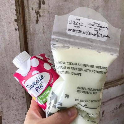 Sweetie Pie Organics Lactation Smoothie held with a breast milk storage bag full of breast milk