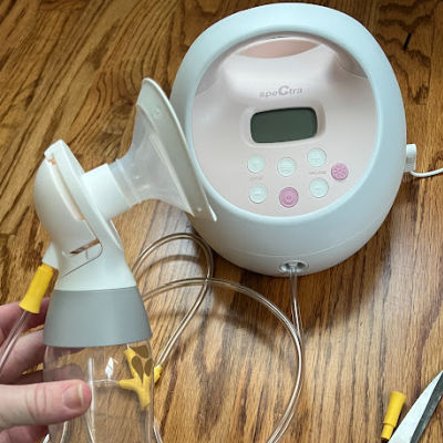 Woman holding Medela pump parts in front of Spectra breast pump