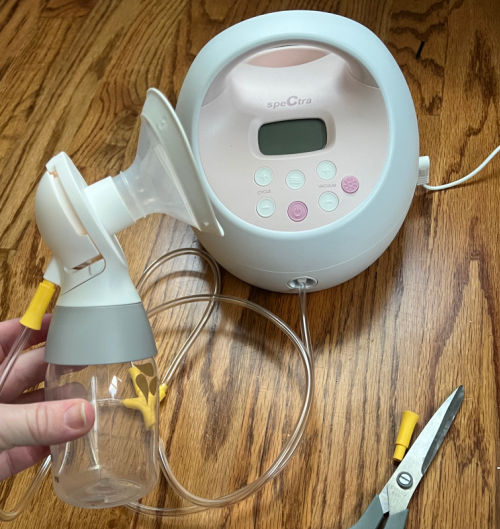 Woman holding Medela pump parts in front of Spectra breast pump