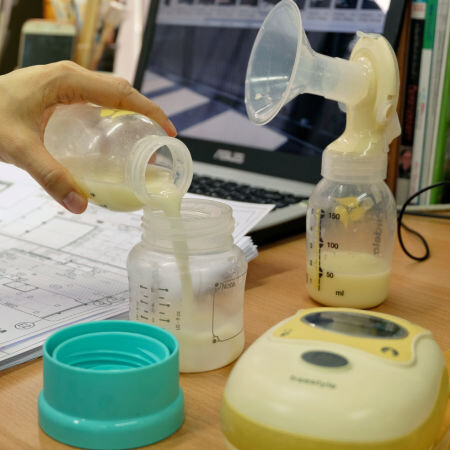 woman pouring breast milk from one bottle into another