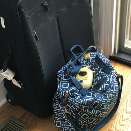 breast pump on a breast pump bag with a suitcase in the background