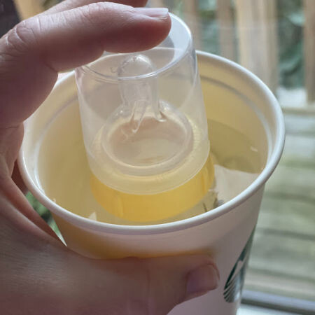 Medela bottle of breast milk warming in a starbucks cup