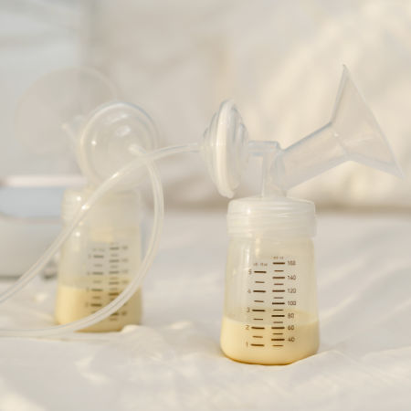 the breast milk are in the bottles of electric breast pumping set on a bed