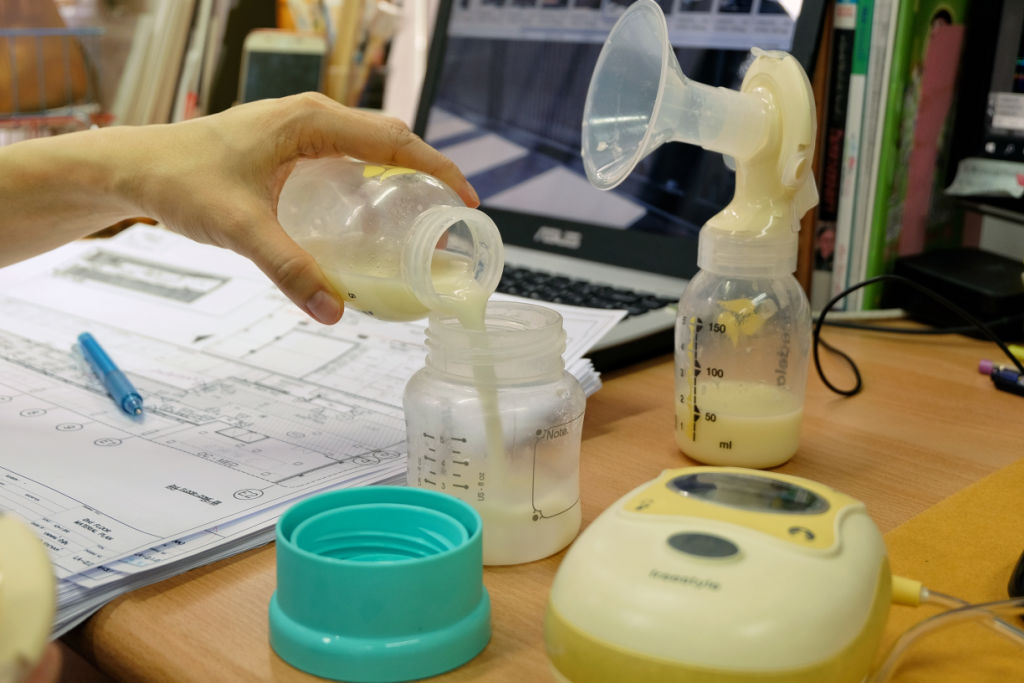 woman pouring breast milk from one bottle to another after pumping at work
