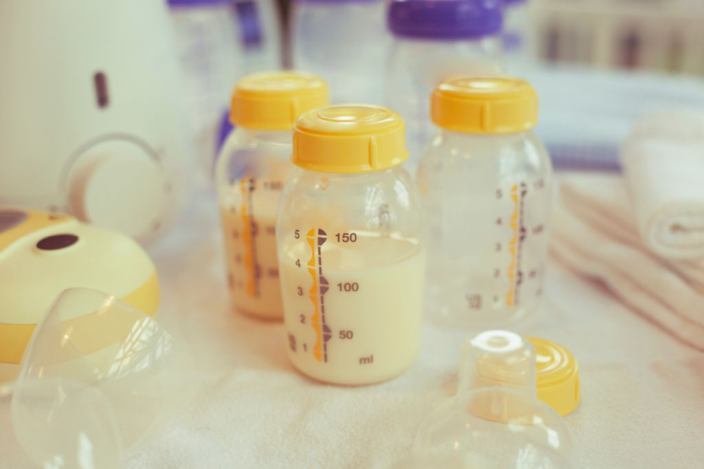 Medela breast milk bottles in front of a breast pump