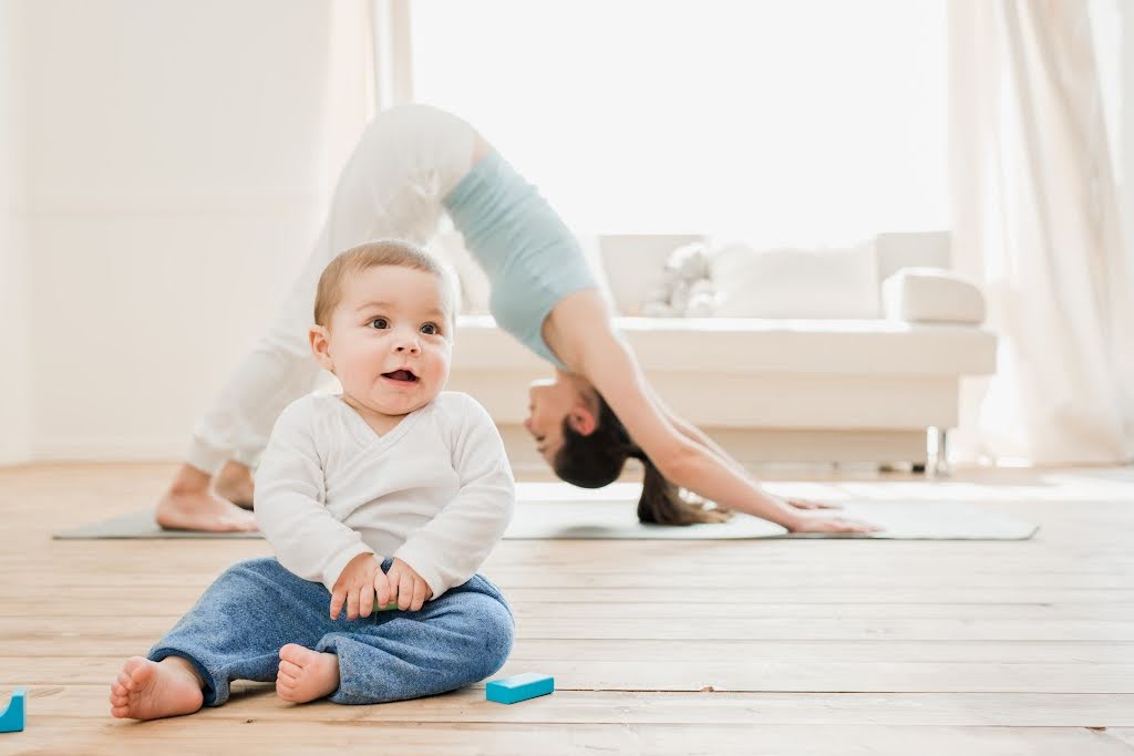 woman doing yoga with baby in the foreground