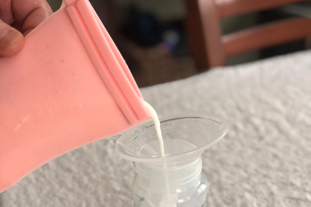 woman pouring breast milk from reusable breast milk bag into a bottle