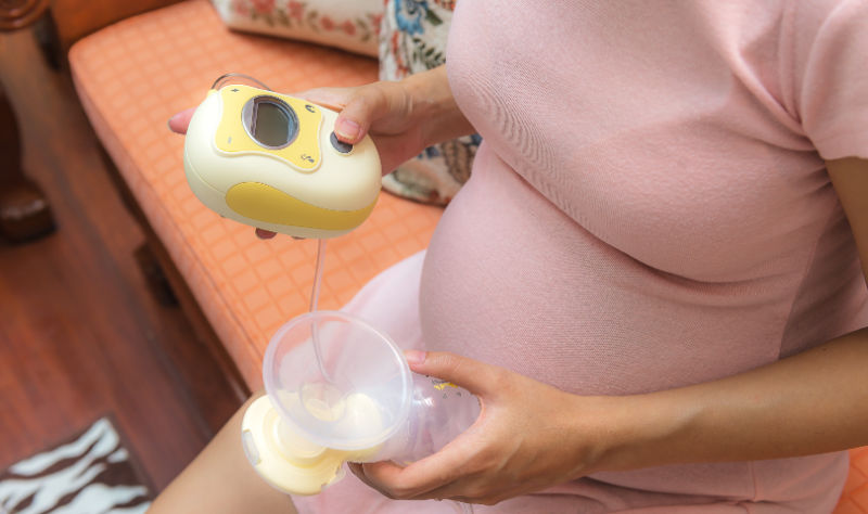 pregnant woman looking at a breast pump