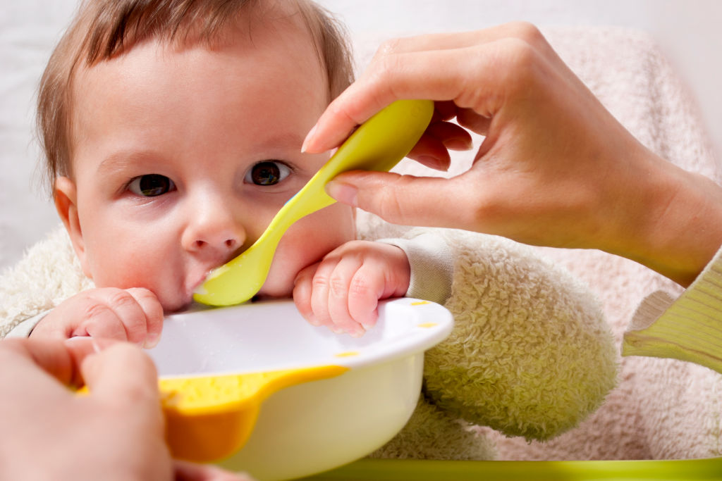 baby being fed solids with a spoon