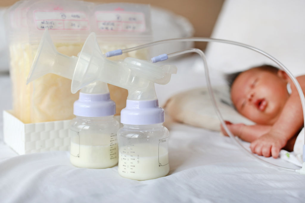 breast milk bottles with baby in the background