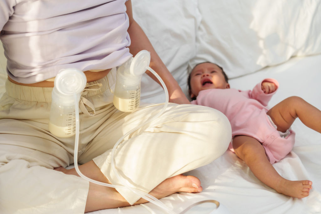 woman pumping breast milk with her baby