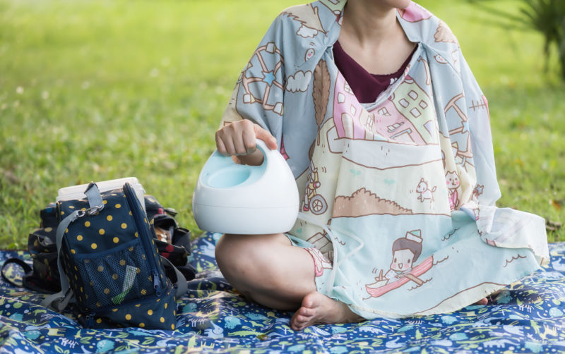 woman pumping breast milk with nursing cover