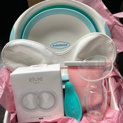 a box with pink tissue paper containing an Elvie Curve, a Haakaa, a Lavie lactation massager, a pink Junobie bag, a davin & adley bra liner, and a wash basin