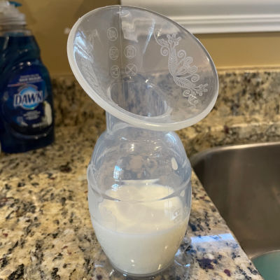 haakaa silicone breast pump with a few ounces of breast milk sitting on a granite countertop