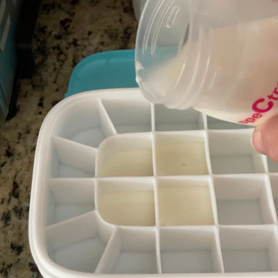 woman pouring breast milk from a Spectra into an ice cube tray of a Ceres Chill Milkstache