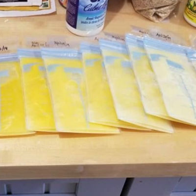 breast milk bags containing breast milk of varying shades of orange/yellow lined up flat on a counter with the darkest orange on the left and the lightest yellow on a the right